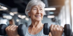 Woman smiles while lifting dumbbells in a gym, wearing a sleeveless top. 