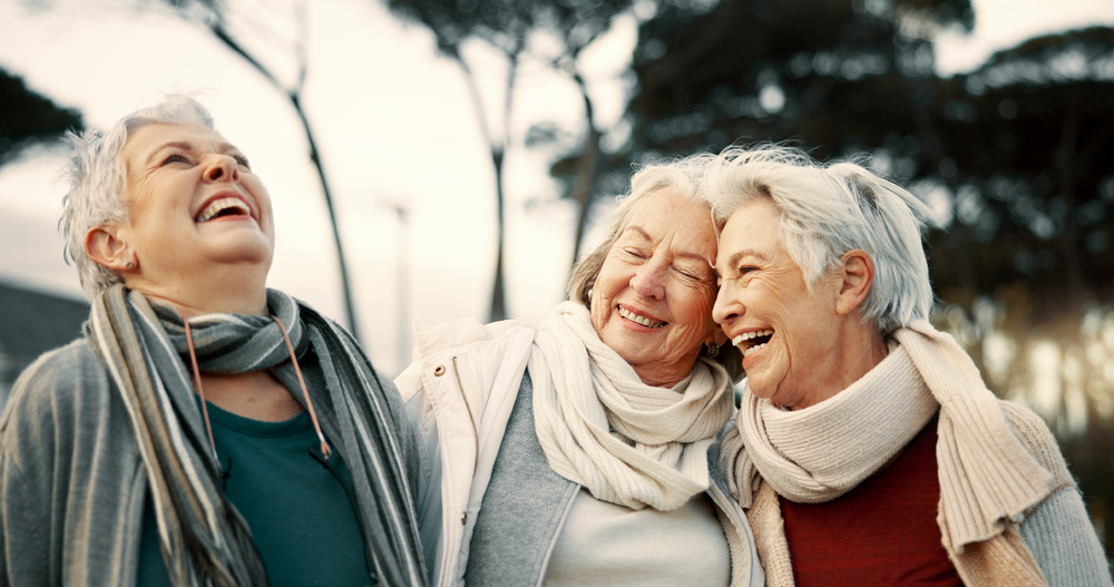 Friends together outdoors, dressed warmly in scarves and sweaters.