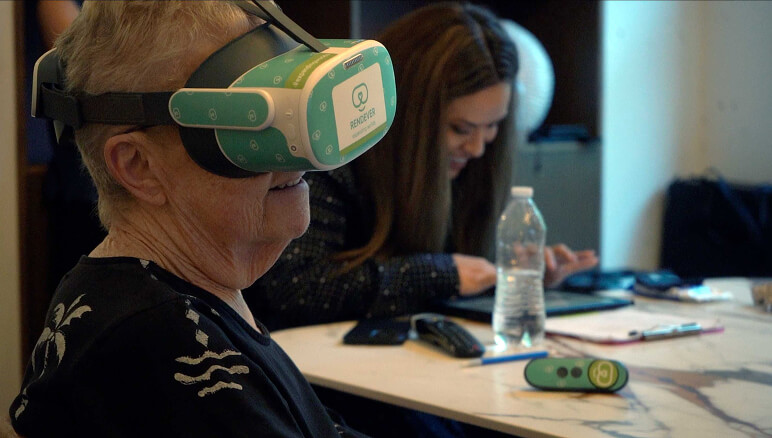Woman smiles while wearing a virtual reality headset, seated at a table