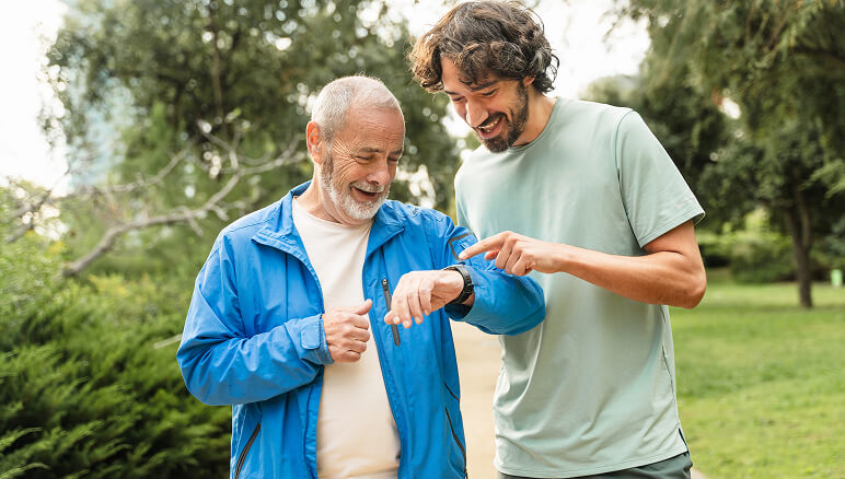 A smiling man in a blue jacket looks at his smartwatch