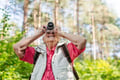 Smiling woman taking photo on nature walk.