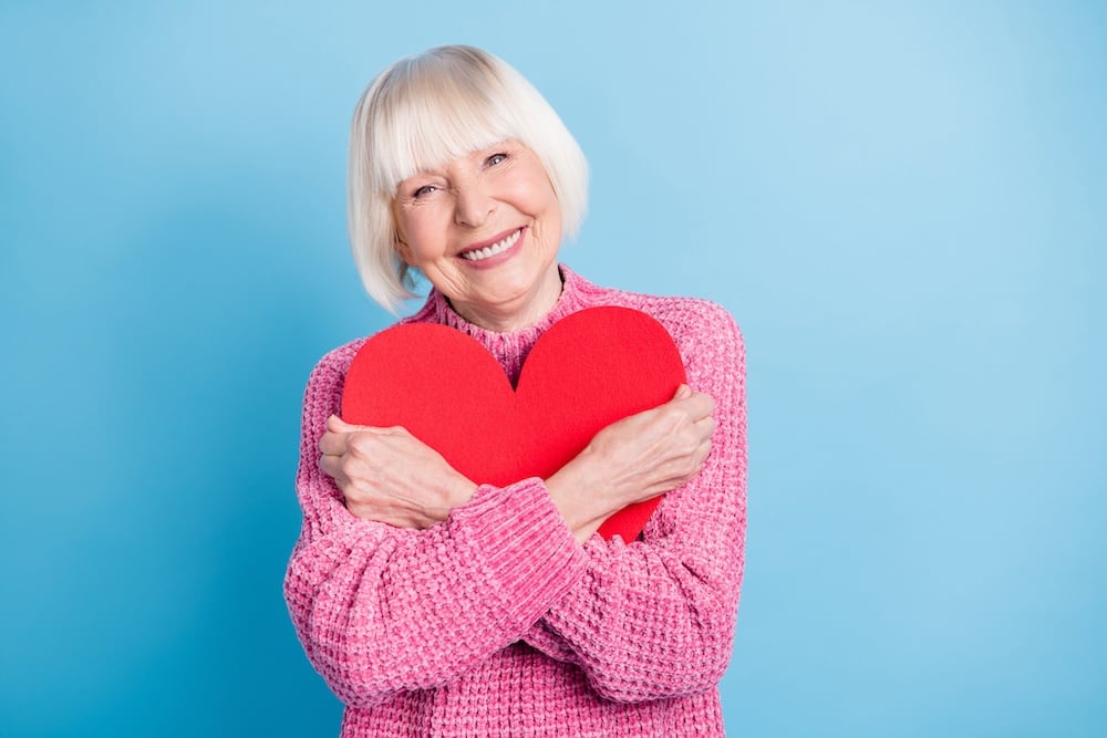 Woman smiling hugging heart cutout